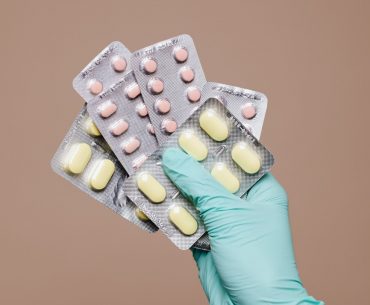 3 gloved person holding medicine